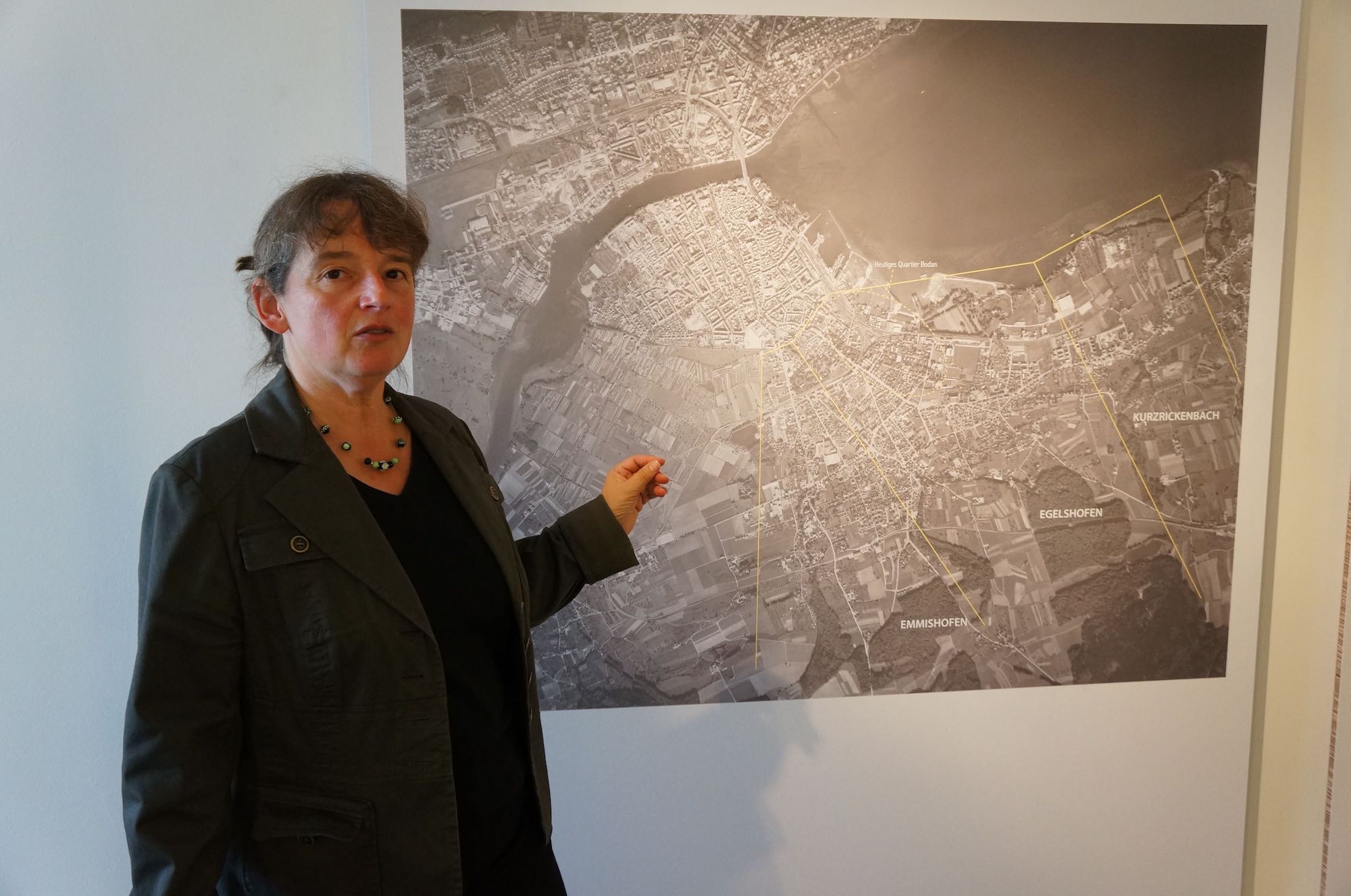 Dr. Yvonne Istas vor einem historischen Luftbild von Kreuzlingen